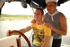 Cute stud wearing yellow and white shirt and jeans and a horny sailor in black and white striped shirt, white hat and black pants suck each others cocks on a yacht before he bangs his asshole from behind. - Picture 1