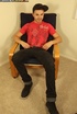 Gorgeous dude sits on a black chair then slowly strips off his red shirt