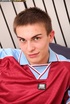 Cute soccer star in maroon and blue uniform takes off his shirt and expose