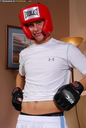 Boxing champ takes off his white shirt and shorts then displays his hunk body wearing his red head gear, blue cycling shorts and black gloves before he gets naked and bares his hard cock in different poses on a brown couch. - Picture 3