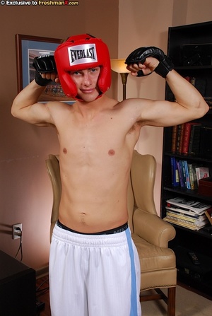 Boxing champ takes off his white shirt and shorts then displays his hunk body wearing his red head gear, blue cycling shorts and black gloves before he gets naked and bares his hard cock in different poses on a brown couch. - Picture 4