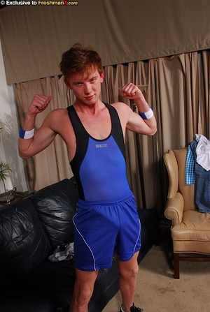Redhead gay dislays his skinny body in black and blue spandex before he gets naked and reveals his large cock on a black couch. - Picture 3