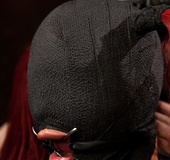 Perky girl’s read hair sticks out of a black mask that covers her face
