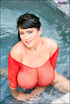 Dark haired babe in a red fishnet outfit posing with joy