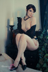 Tall slender beauty sits on her night stand and plays with her pussy