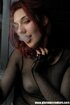 Goth girl in fishnets smokes a cigarette next to a window and plays with