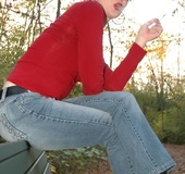 Nerd brunette on a park bench smokes and licks her red lipstick