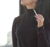 Modern bitch in black smokes for the camera outdoors in the cold
