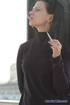 Modern bitch in black smokes for the camera outdoors in the cold
