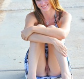 While sitting on the sidewalk in colorful dress shows pussy and clit