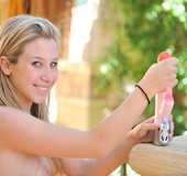 Perky young blond brings her toy outside and teases her shaved and wet