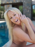 Young blonde with a shiny smile posed naked by the pool