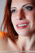 Redhead in fishnet stockings gets on the floor and teases her pussy.