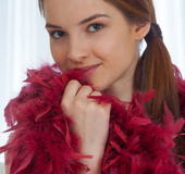Naked brunette babe poses with leg wide open and red feather boa.