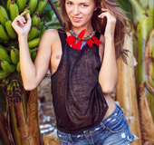 Brunette goes to banana garden, gets naked and poses on banana stump.