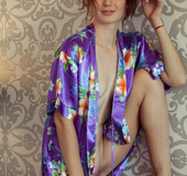 Redhead exposes her very smooth pussy on a purple couch.