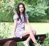 Brunette girl takes a hike in nature and gets naked on bench.