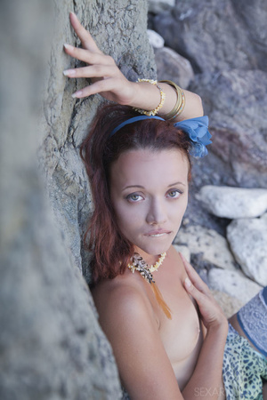 Beautiful brunette babe lies on rocks by - Picture 12