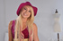Blonde temptress in red dress and hat and spotted lingerie flaunts ass