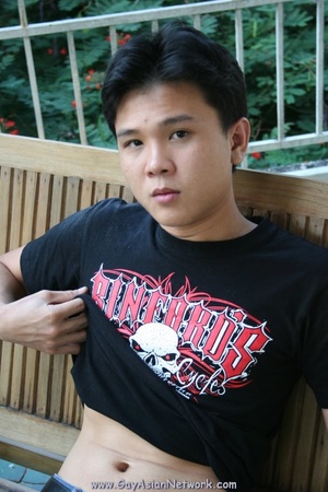 Handsome Asian guy sits on a wooden couc - Picture 3