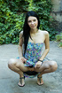 Chick in sexy dress bends hot outdoor by green bushes