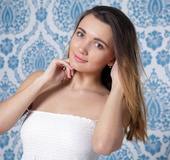 Chick in white blouse strips by blue traced wall on white couch