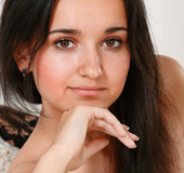 Black haired young lady with tan lines shows herself off atop a white