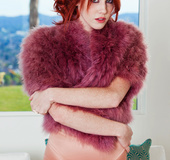 Skilled redhead in a orange satin garment and fur burgundy coat posing