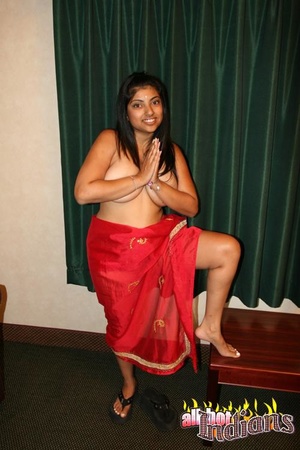 Dark haired indian in red saree undressing on a cam and exposing her big boobies while posing on the table - Picture 4