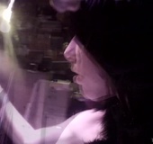 Dark haired cutie is posing naked in a dark room, caressing her sexy body