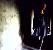 Black skirt and jacket wearing brunette wanders through concrete pillars