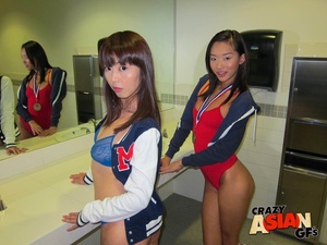 Two perfect Asian dolls tend to a guy’s length in a locker room. - Picture 1