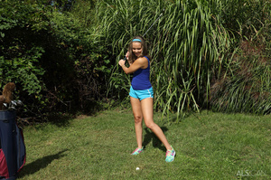 Young flexible chick strips and squirts on the greens during a game of golf - Picture 1