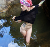 Young girl with pink hair lies in the lap of nature as she pleasures herself