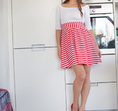 Magnetic brunette wearing white top and red striped skirt shows off her