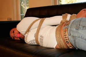 Pretty brunette in jeans and white top ball gagged and hog tied with ropes on sofa - XXXonXXX - Pic 12