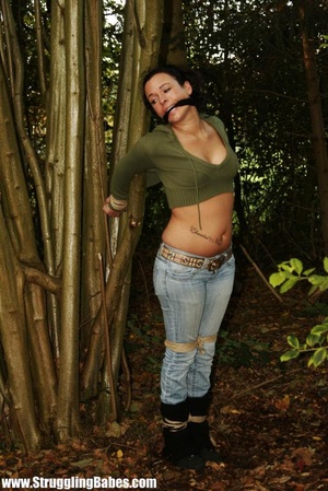Lusty brunette in jeans pants and green top gagged and tied to bamboo tree - Picture 8