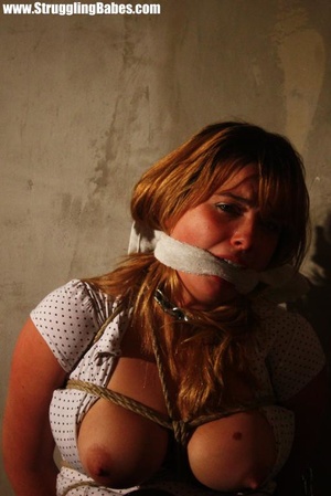 Busty brunette in white top and black pants gagged, roped and bound - Picture 12