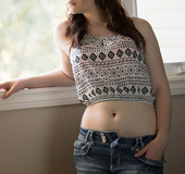 Curvy brunette takes off her jean shorts and pink bra to pose