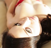 Posing on a couch from a blue-eyed, busty lady in red