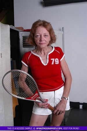 Luscious granny pose her old body while holding a tennis racket before she expose her small tits wearing her red shirt and white shorts. - Picture 5