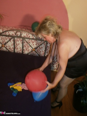 Blonde cougar plays with balloons and shows her massive tits to the cam - Picture 15