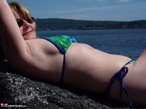 This blonde tramp in a bikini shows off her slutty body as she poses beach-side - Picture 11