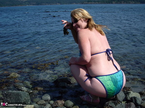 This blonde tramp in a bikini shows off her slutty body as she poses beach-side - Picture 19