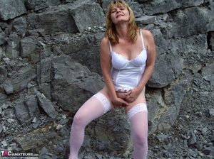 A blonde grandma squats down and spreads her wet pussy for the camera in the woods - Picture 10