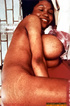 This older, ebony, slut smiles as she displays her large tits