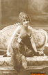 She poses in a white dress and smiles seductively from the couch