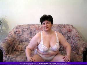 Fat granny displays her enormous body in white underwear and black high heels on a pink and purple couch before she takes off her bra and expose her large tits then pulls down her panty and bares her hairy crack in different poses. - Picture 1