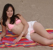Teen hottie displays her skinny body as she lays down on a multi colored