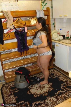 [Cute babe pose her chubby body in gray shirt, black jogging pants and boots in a sex shop before she gets naked and puts on her violet and black nighty, black stockings and high heels in a fitting room. - Picture 10